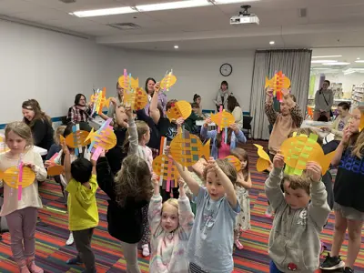 Crowd of kids at Wildlife Wednesdays program holding paper fish craft