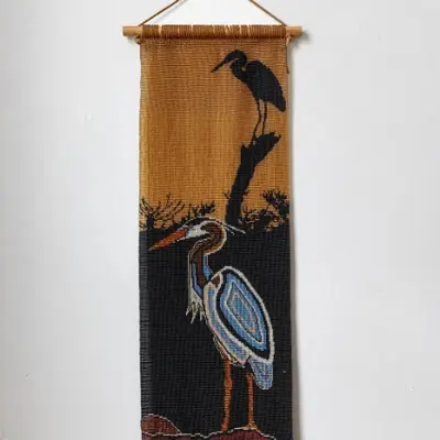 Beaded tapestry of two cranes hanging on a white wall